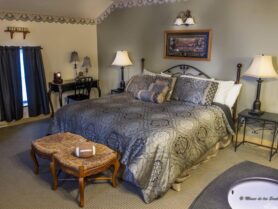 bed with brown bedspread, lamps, bench with football