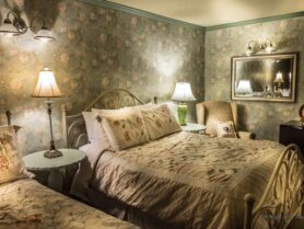 bedroom with floral wallpaper and 2 beds, lamps