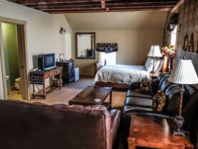 The Iowa Grand Oak Room with sofas and bed, tv, vanity sink